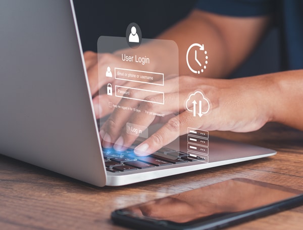 Person die an einem Laptop tippt, während ein transparentes digitales Login-Fenster mit Eingabefeldern für Benutzername und Passwort über dem Bildschirm eingeblendet ist